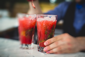 Beautiful line of different colored alcohol mojito cocktails with mint on a open air party, tequila, martini, vodka, and others on decorated catering bouquet table on open air event party.