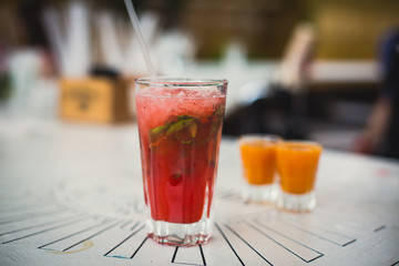 Beautiful line of different colored alcohol mojito cocktails with mint on a open air party, tequila, martini, vodka, and others on decorated catering bouquet table on open air event party.