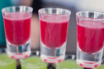 Beautiful line of different colored alcohol mojito cocktails with mint on a open air party, tequila, martini, vodka, and others on decorated catering bouquet table on open air event party.