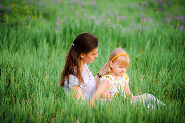 Cute cheerful blond girl playing in the park with her mother