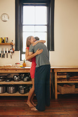 Cheerful young couple embracing each other in kitchen