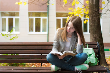 Student reading book on bench