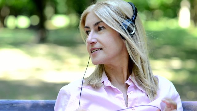 Portrait of a woman listening music in a park