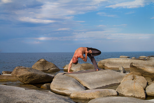 
man practicing yoga near the sea