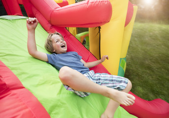 Fototapeta na wymiar Child on inflatable bouncy castle slide