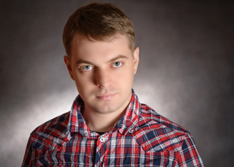 Sad young man, portrait on the dark background.