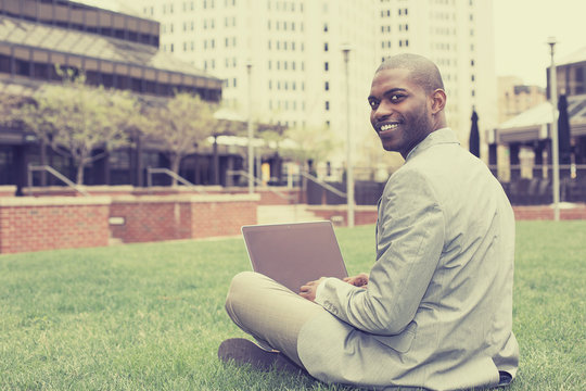Handsome businessman working with laptop sitting outdoors