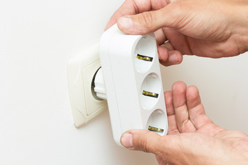 Hands inserting electrical tee adapter into the socket