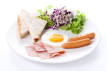 Plate of breakfast with fried eggs, toast, ham, sausage and vegetables