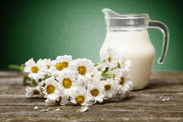 Milk and flowers on a wooden background