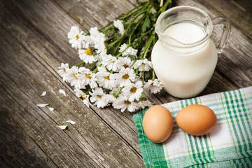 Milk and flowers on a wooden background