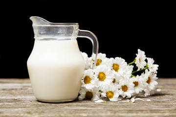 Obraz na płótnie Canvas Milk and flowers on a wooden background