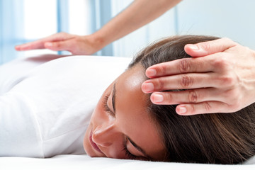 Therapists hands doing reiki therapy on girl.