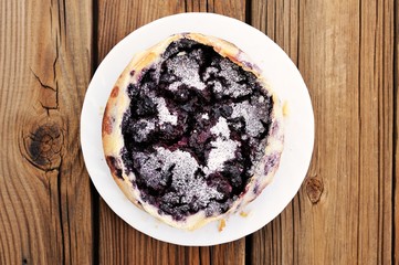 French pie clafoutis with berries and cracks on icing sugar in w