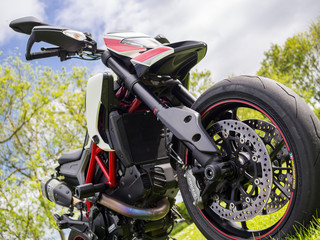 A supermotard type motorcycle in field in early summer (front part)