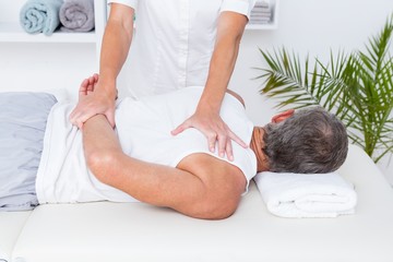 Obraz na płótnie Canvas Physiotherapist doing shoulder massage to her patient