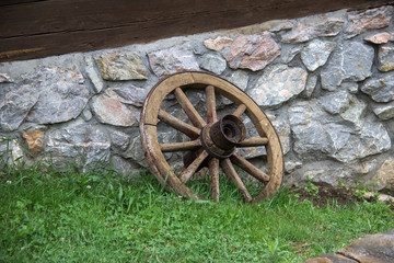 Fototapeta premium Old Wagon Wheel / Old Wagon Wheel against an Old Historic House Wall.