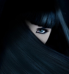 mysterious brunette wth hai covered face and aquamarine eyes