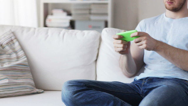 close up of man playing game on smartphone at home