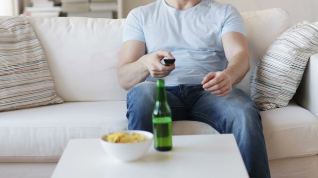 close up of man with beer and remote at home