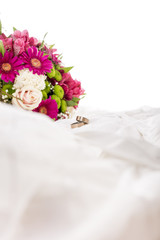 Beautiful colorful bouquet of flowers and two wedding rings on w