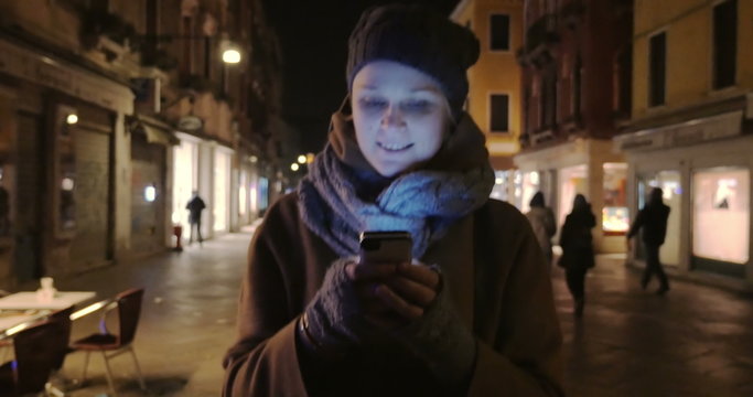 Woman walking at night and chatting on cell phone