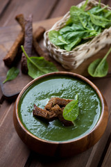 Spinach cream-soup with croutons in a wooden bowl, vertical shot