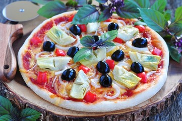 Healthy pizza with artichokes, olives, onions, peppers, basil and olive oil