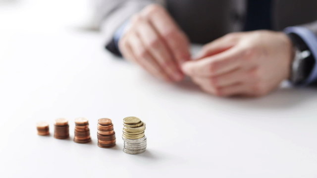 close up of businessman putting coins into columns