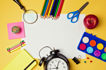 Back to school background with blank white paper and school supplies. View from above
