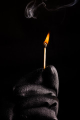 Close-up of hand with match flame
