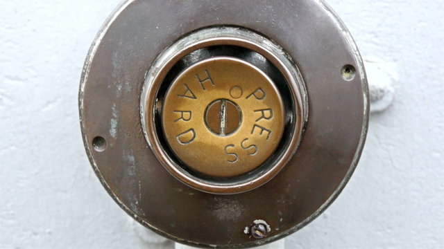 A button that says press hard. It is brown in color with the letters on it