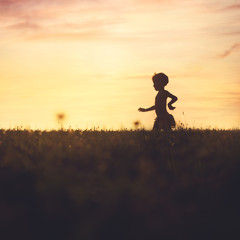 carefree baby running in the field at sunset
