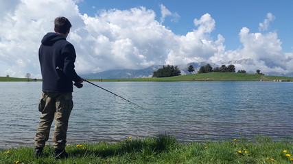gar&ccedil;on p&ecirc;chant dans un lac de montagne