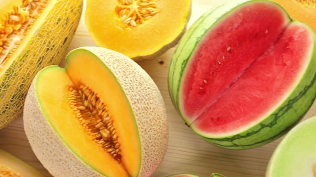 Variety of organic melons sliced on wood table.