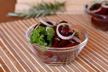 Fresh sliced beetroot salad with onion and parsley on a glass bowl