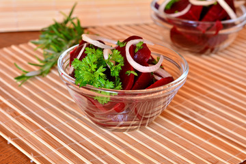 Fresh sliced beetroot salad with onion and parsley on a glass bowl