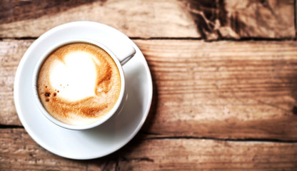 Coffee cup on a wooden table, top view. Dark background.