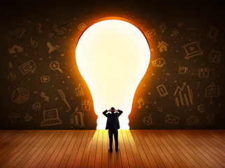 Obraz premium Business man looking at bright light bulb in the wall