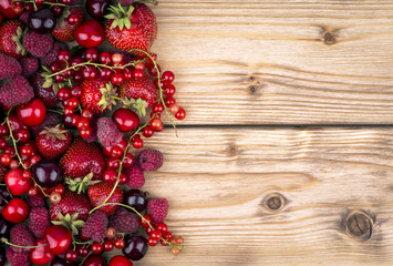Fototapeta na wymiar Strawberries, currants, raspberries and cherries on the wooden background.