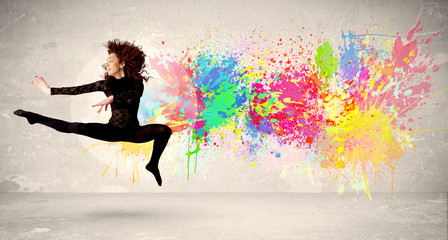 Fototapeta na wymiar Happy teenager jumping with colorful ink splatter on urban backg