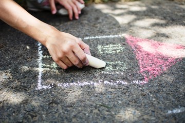 Children draw in the park with chalks of various colors. Selective focus on hand.