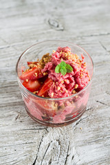 frozen yogurt with strawberries and cookie crumbs in a glass bowl on a light wooden background