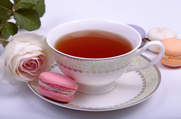 Obraz na płótnie Canvas Cup of tea with pink french macaron and pastel rose