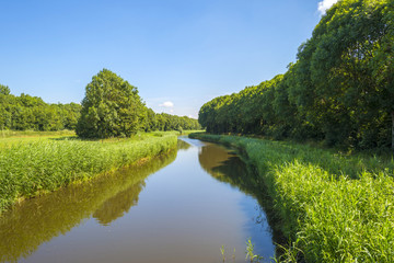 Fototapeta premium Canal through sunny farmland in summer