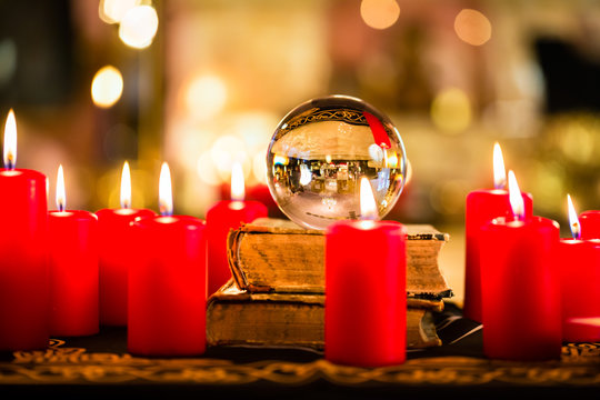 Glaskugel zum wahrsagen oder esoterischem Hellsehen w&auml;hrend einer Seance und Kerzen im Kerzenlicht