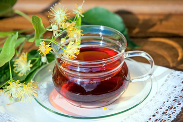 Cup with linden tea and flowers on wooden table