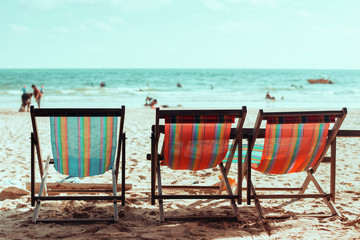 Vintage toned three beach chairs on tropical shore