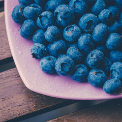 Old bowl of fresh organic blueberries on wooden table.Soft focus