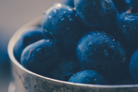 Old bowl of fresh organic blueberries on wooden table.Soft focus